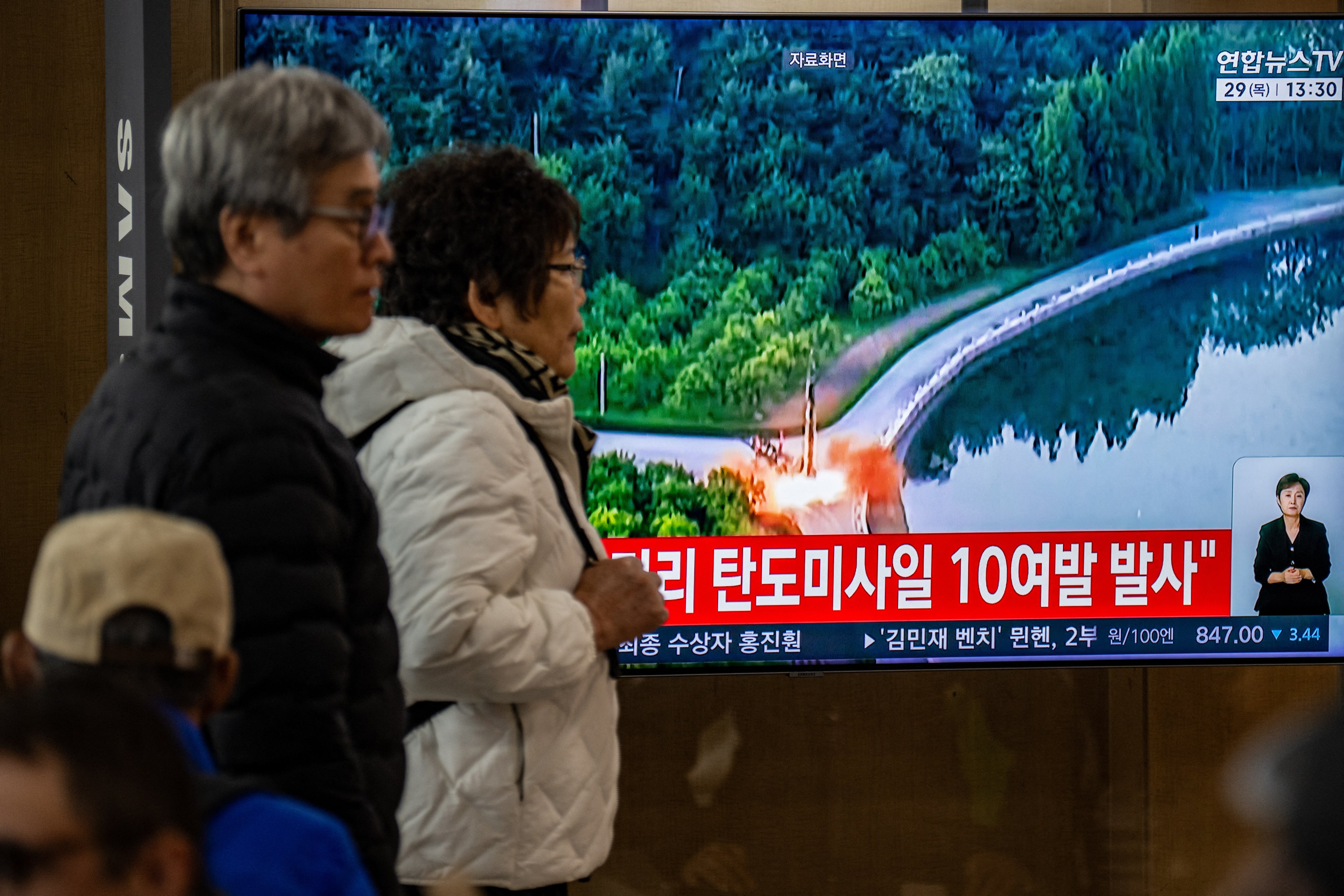 People walk past a screen showing news coverage with file footage of a North Korean missile launch at Seoul Station in Seoul on October 29, 2026 (AFP/Getty)