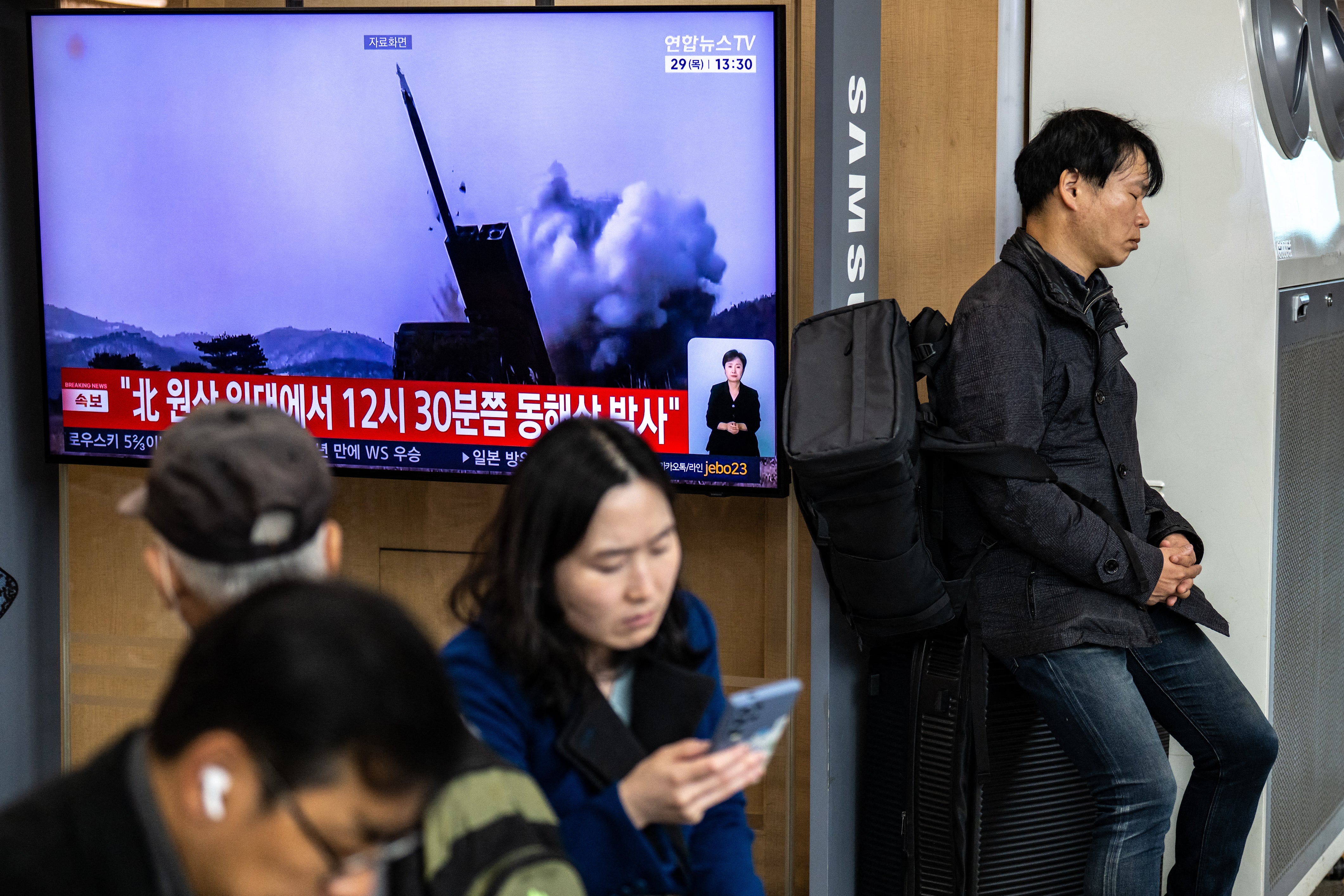 People sit next to a screen showing news coverage with file footage of a North Korean missile launch at Seoul Station in Seoul on October 29, 2026 (AFP/Getty)