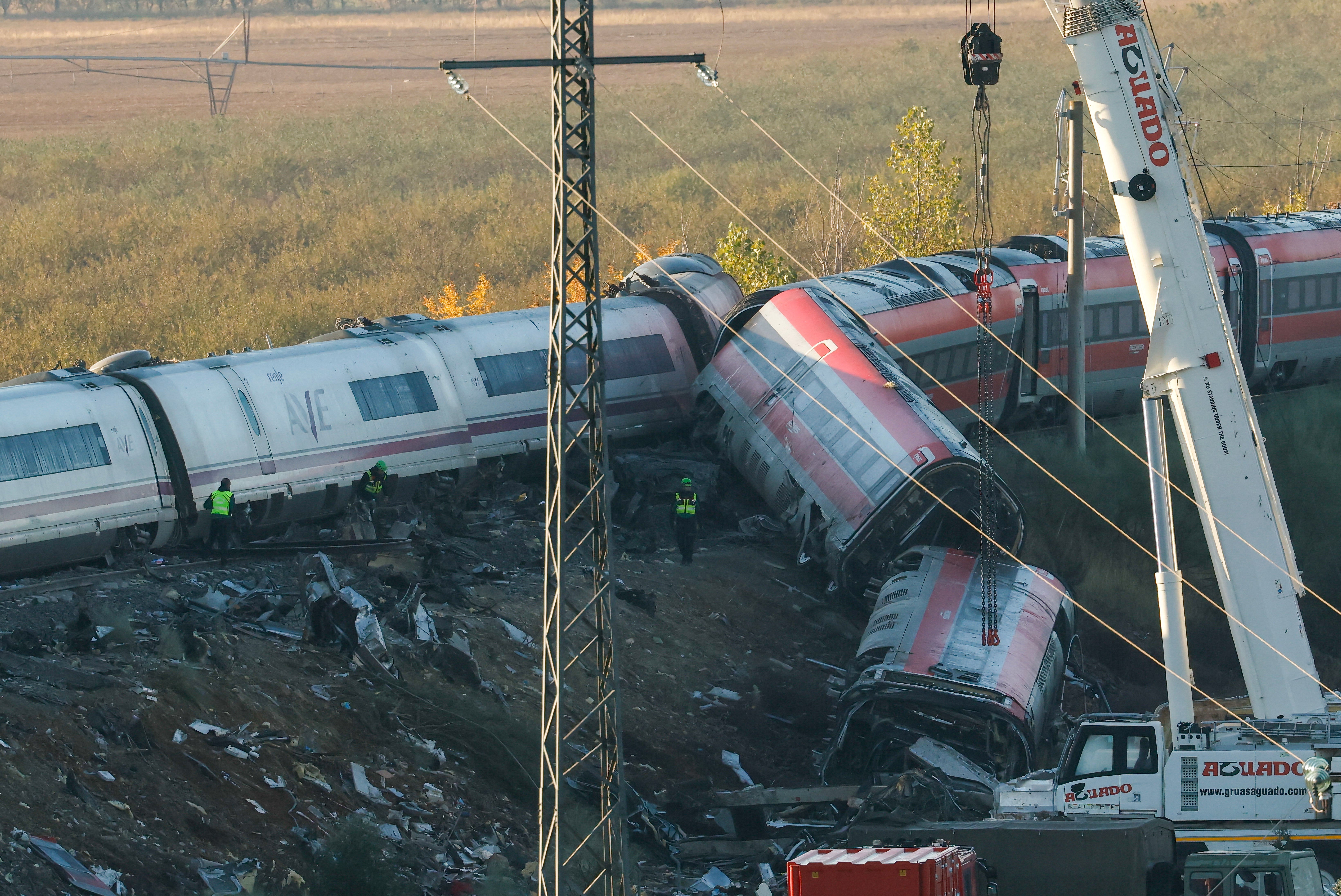 Investigators use heavy machinery to remove damaged carriages from the train crash