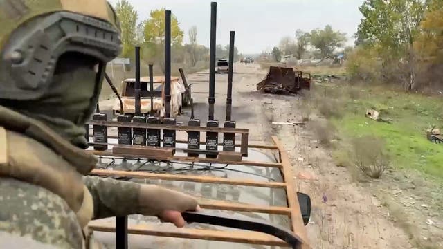 Russian military personnel pass by damaged vehicles during a demining operation in video published on Thursday ( Reuters )