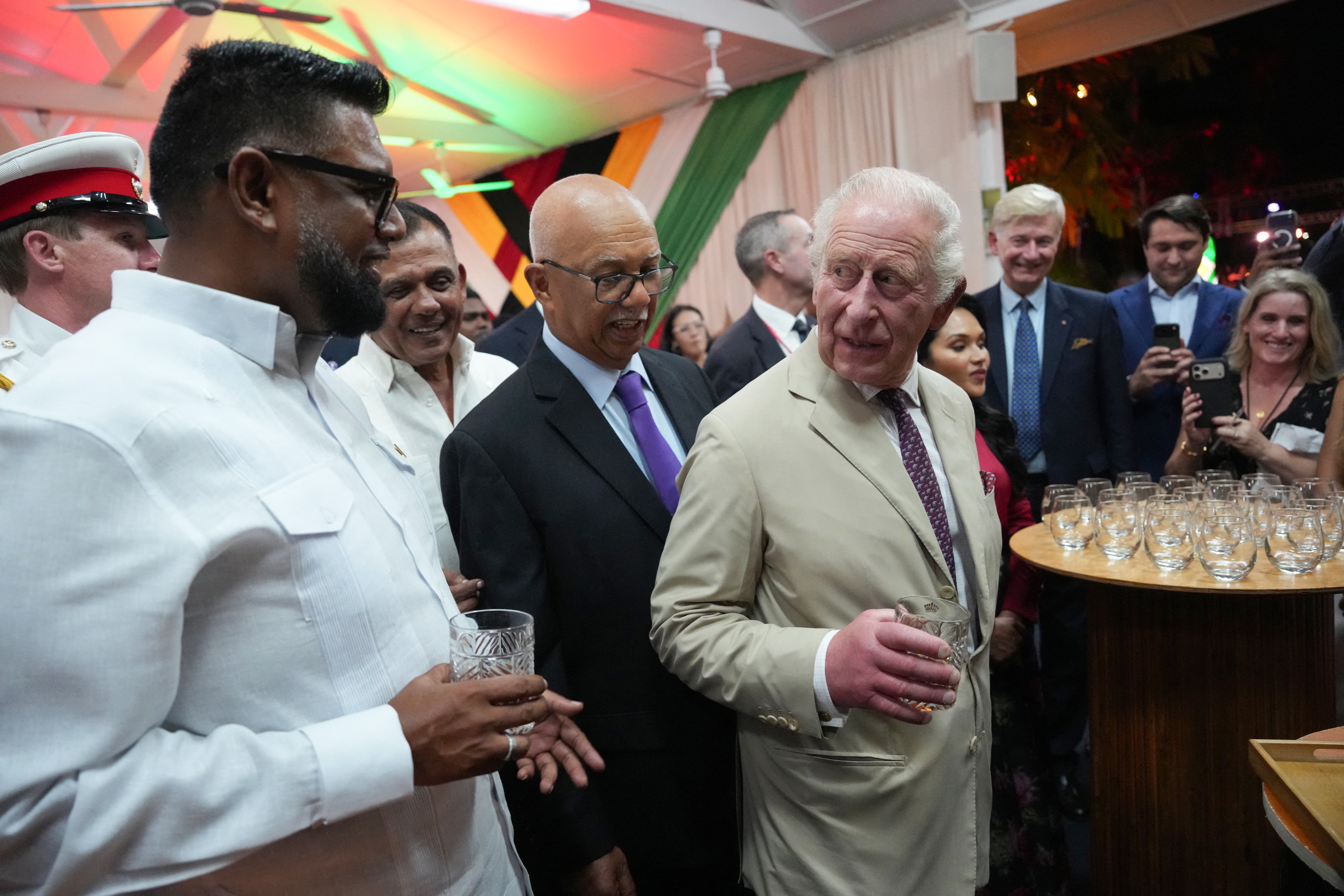 King Charles III (R) holds a glass of a specially produced Guyanese rum created in his honour as he speaks with Guyanese President Mohamed Irfaan Ali during a State Reception at the State House in Georgetown