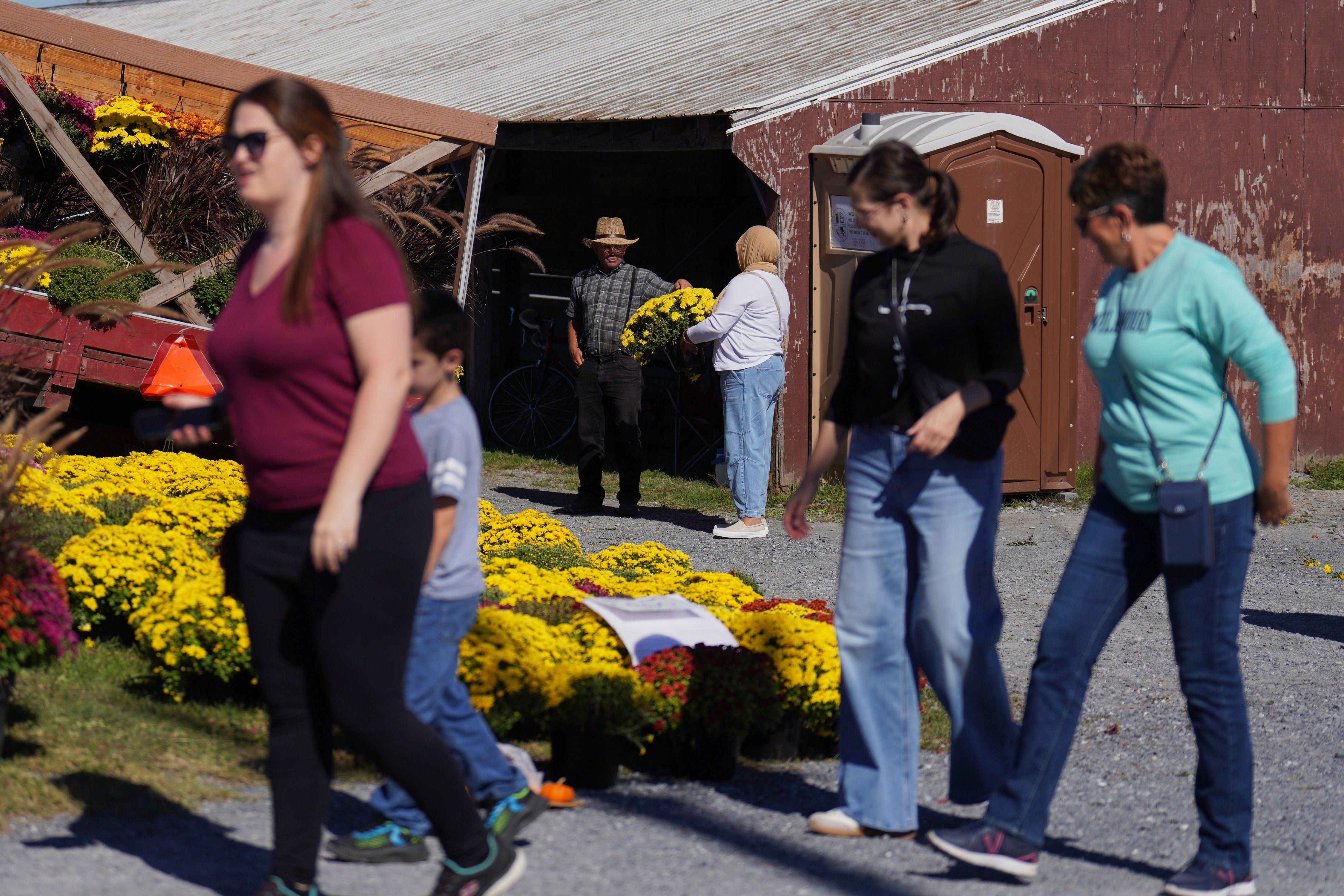A member of the Plain community, center left, sells flowers at The Green Dragon Farmers Market and Auction in Ephrata