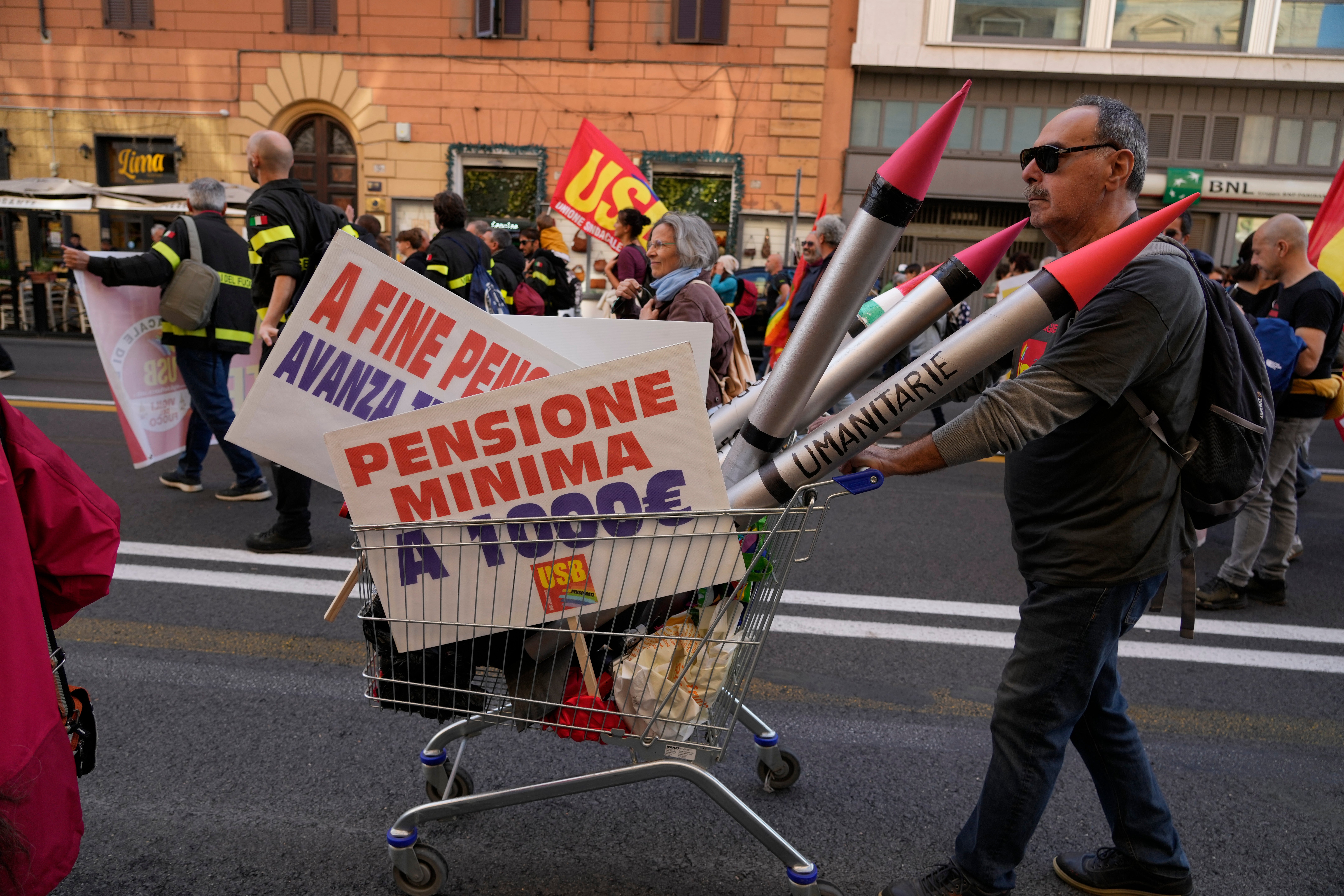 A demonstrator pushes a shopping cart carrying mock missiles and placards calling for a minimum pension of 1,000 euros during a protest in Rome