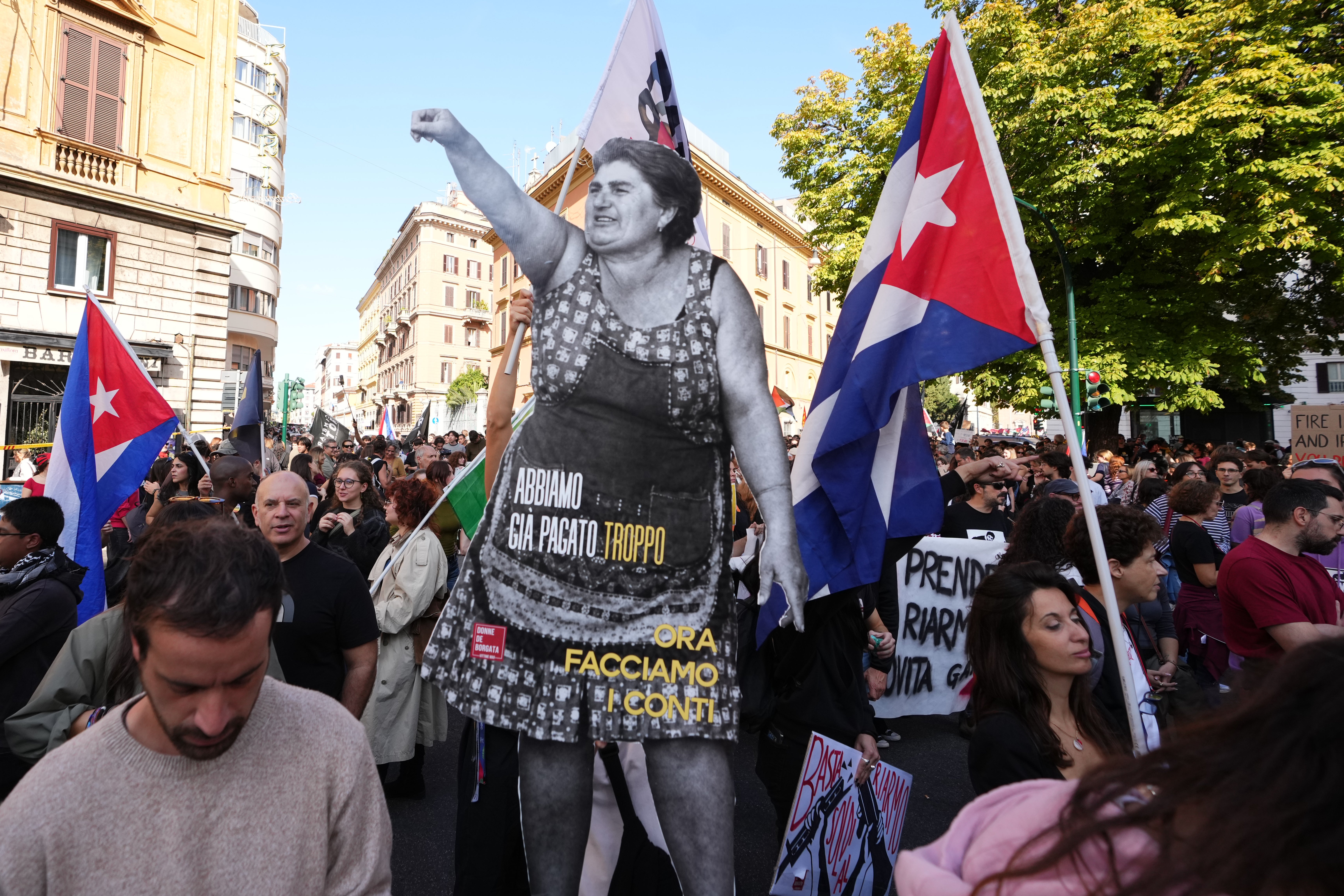 Demonstrators carry a life-size cutout of a woman raising her fist, with a message reading "We've already paid too much, now let's settle the score," during a strike in Rome on Friday