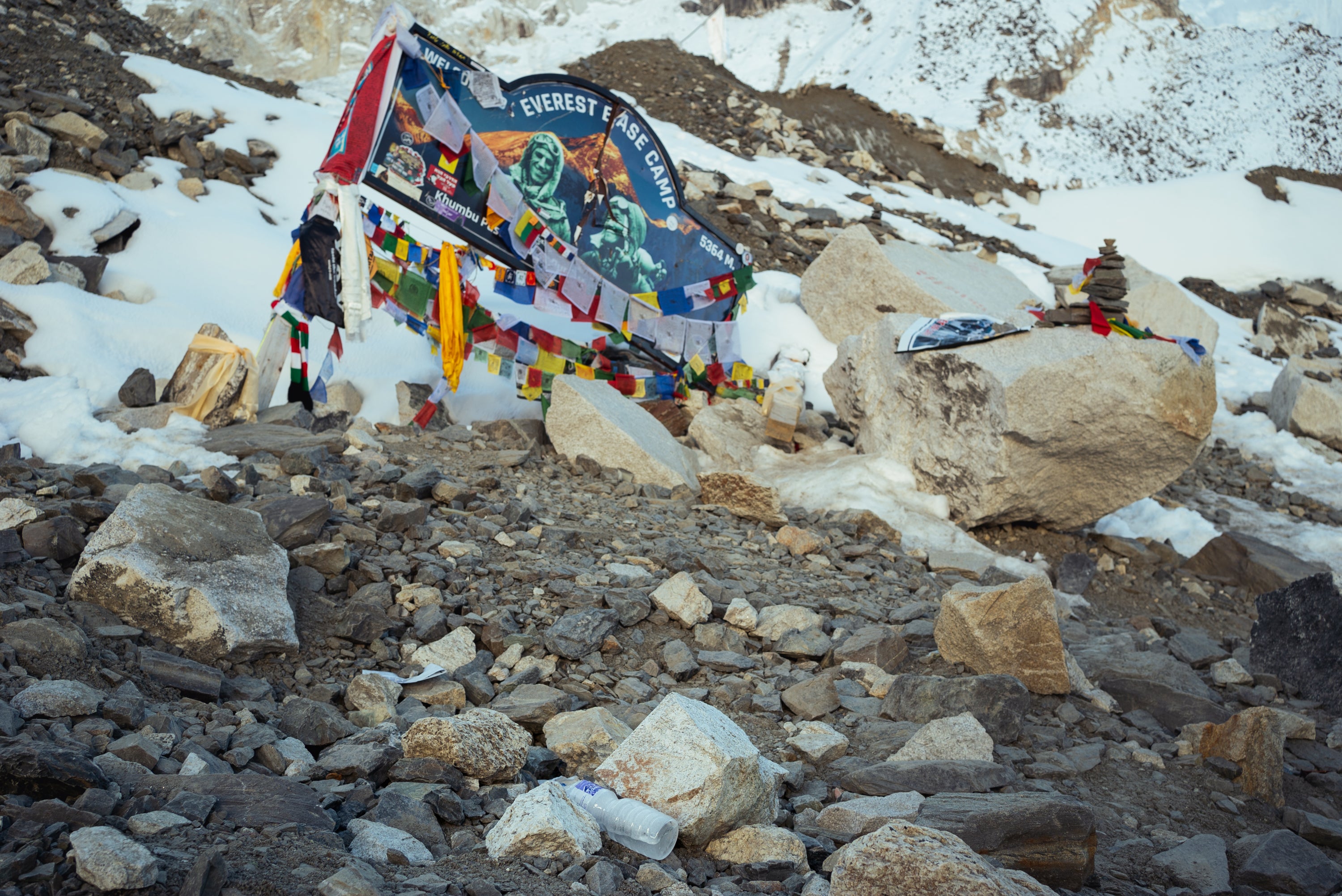 A plastic water bottle lies abandoned next to the 'Everest Base Camp' signage