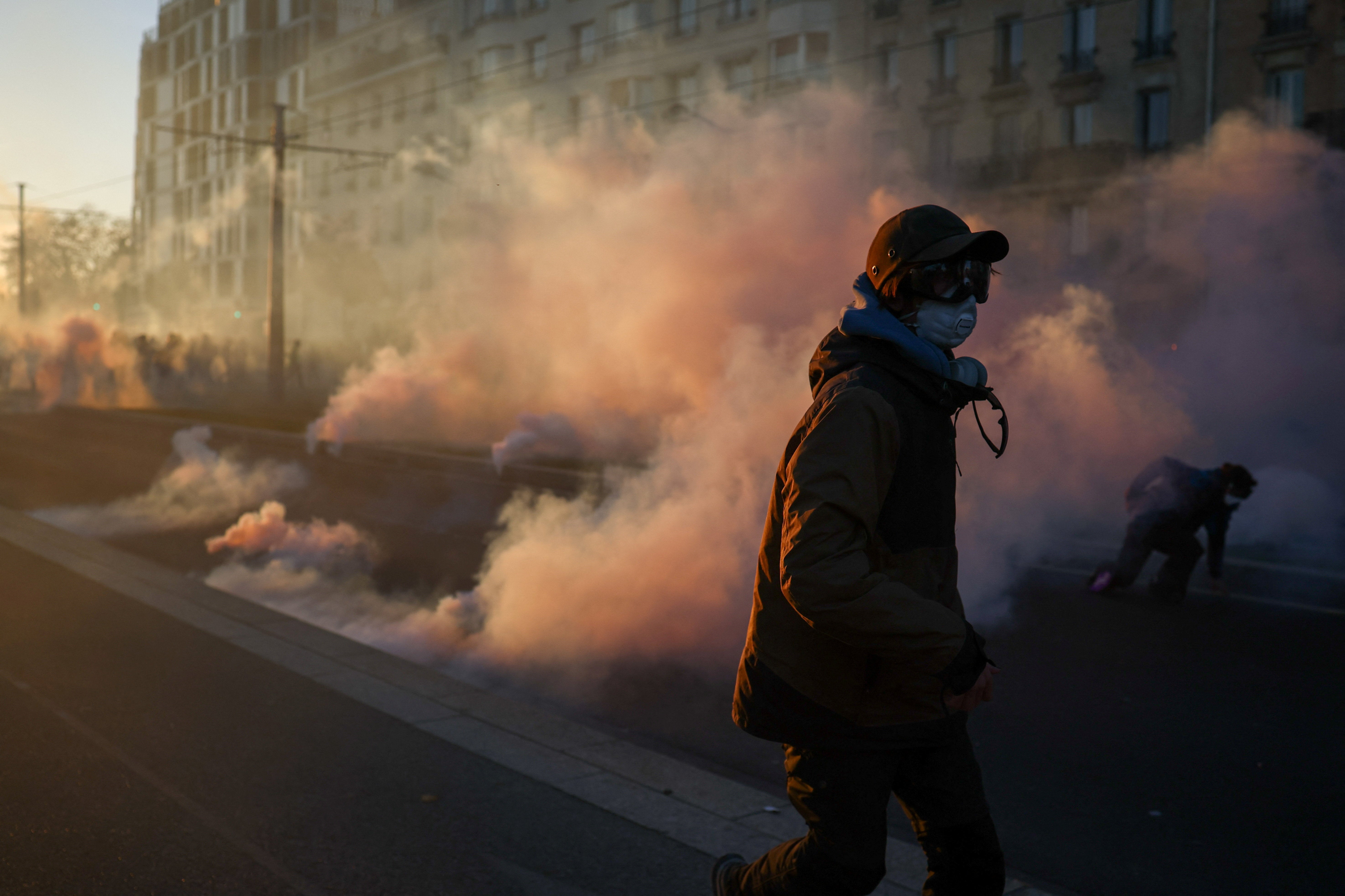 Protesters run amid tear gas, during a demonstration organised by labour unions in Paris