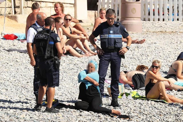 A woman being told to remove her burkini by police in France