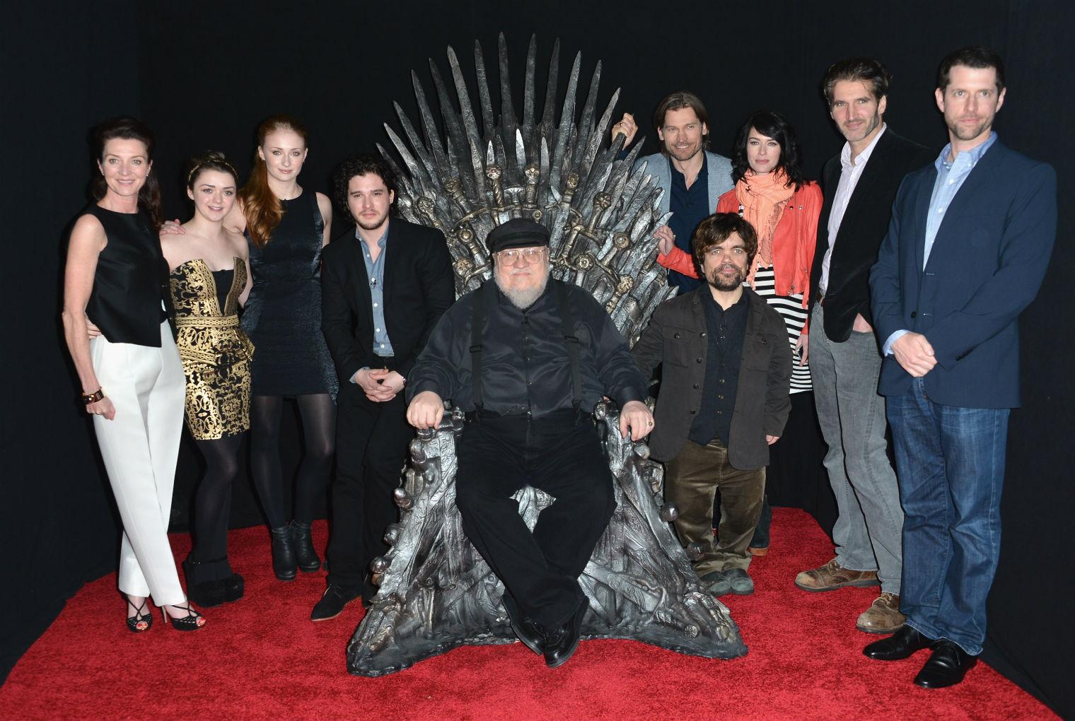 George RR Martin sitting on the Iron Throne from the set of ‘Game of Thrones’, the hit show based on his books, with members of the cast
