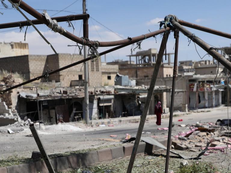 idlib-A-woman-walks-along-buildings-dama