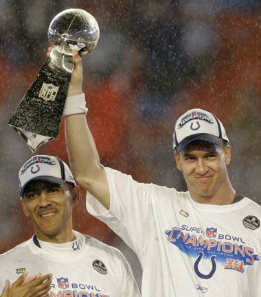 Manning - with Colts coach, Tony Dungy - lifts the Vince Lombardi Trophy in a soaking wet Miami