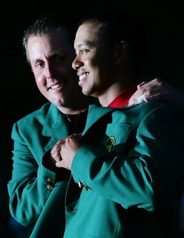 Phil Mickelson presents Woods with his fourth Green Jacket after victory at Augusta in 2005