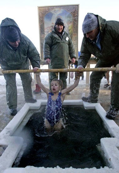 A young girl is plunged into ice cold water to mark Orthodox Epiphany