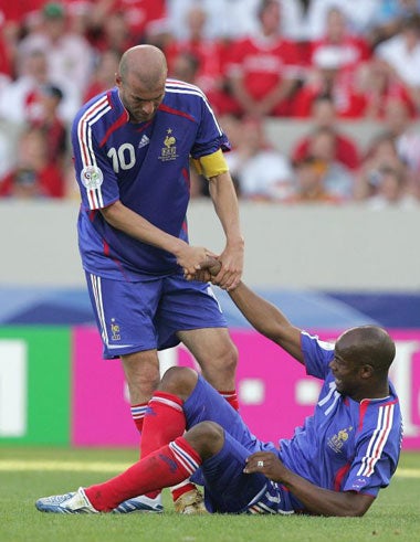 French captain Zidane helps Sylvain Wiltord to his feet as Les Bleus struggle against the Swiss