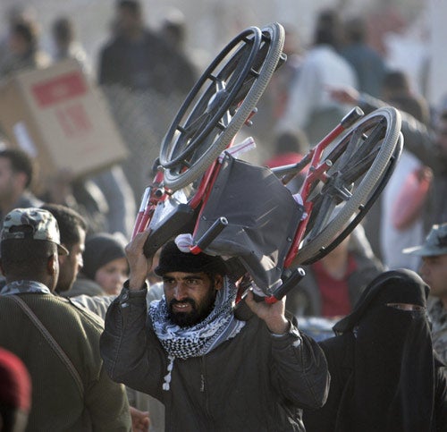 A Palestinian man carries a wheelchair across the boarder back to Gaza