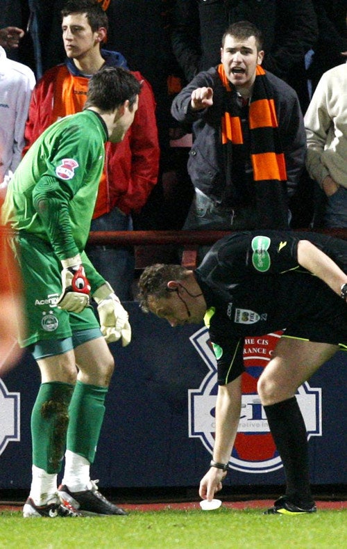 Referee Craig Thomson picks up an object thrown on to the pitch during the CIS Insurance Cup match between Aberdeen and Dundee United