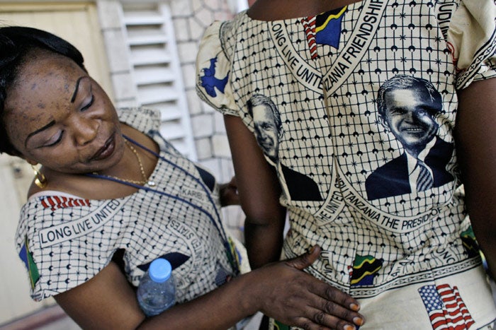 Tanzanian women put the final touches to traditional dresses printed with the portrait of President Bush