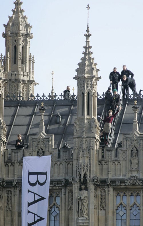 Protesters calling for a halt to the expansion of Heathrow hold paper planes on Parliament's roof