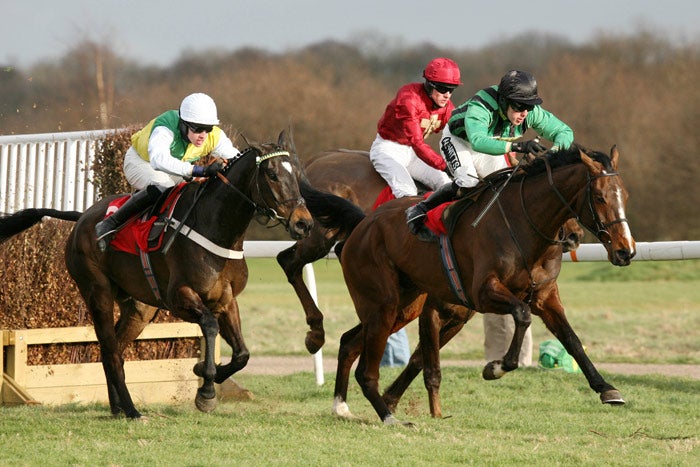 Alderburn leads at the third-last fence, with the eventual winner Cloudy Lane (left) tucked in behind