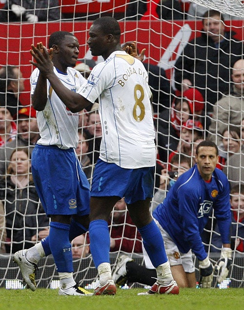 Pompey's Muntari (left) celebrates his decisive penalty as emergency goalkeeper Rio Ferdinand looks on