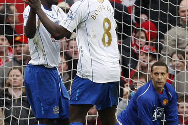 Pompey's Muntari (left) celebrates his decisive penalty as emergency goalkeeper Rio Ferdinand looks on