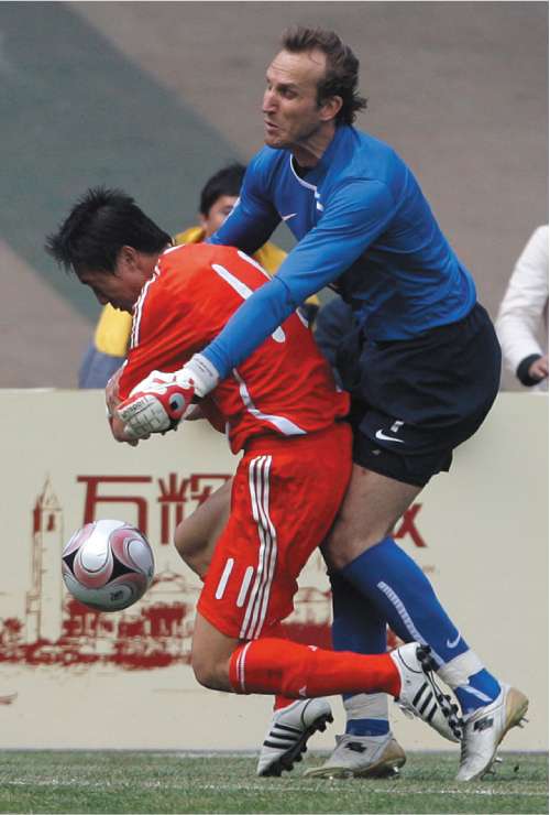 Australia goalkeeper Mark Schwarzer (right) concedes an 89th-minute penalty - whichhe then saved - by fouling China's Qu Bo in Kunming yesterday