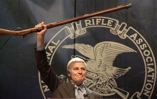Charlton Heston brandishing his rifle after addressing the NRA (Ric Feld/AP)