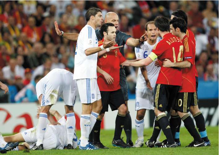 Referee Howard Webb tries to calm down Spanish and Greek players after a foul