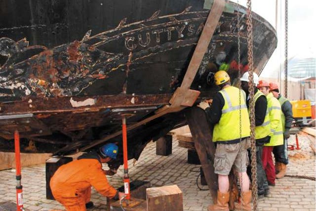 Workmen continue to restore the Cutty Sark after fire nearly destroyed the ship last year