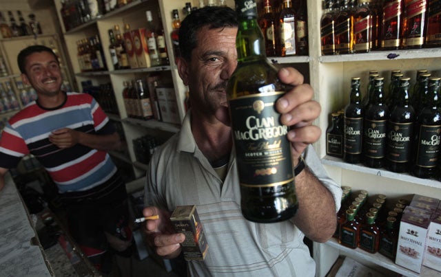 A shop-owner brandishes a bottle of whisky in Baghdad, where drink stores have reopened