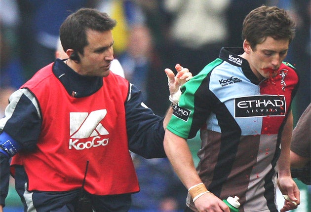 Harlequins winger Tom Williams (right) is escorted from the pitch by the club physio, Steph Brennan