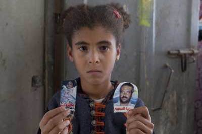 Amal Samouni, aged 10, holds photos of her father and brother, both killed by Israeli troops