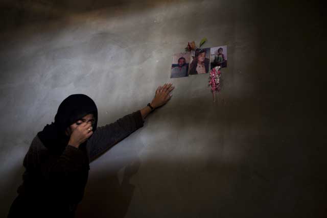 Zeinat Samouni leans against a wall decorated with pictures of her husband Atiya and four-year-old son Ahmad, killed when Israeli troops stormed their home