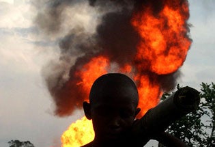 File: A boy walks past the flame from gas flares near Port Harcourt in the Niger delta region of Nigeria