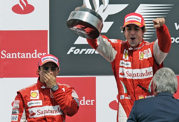 Felipe Massa watches Ferrari team-mate Fernando Alonso celebrate his controversial victory in the German GP