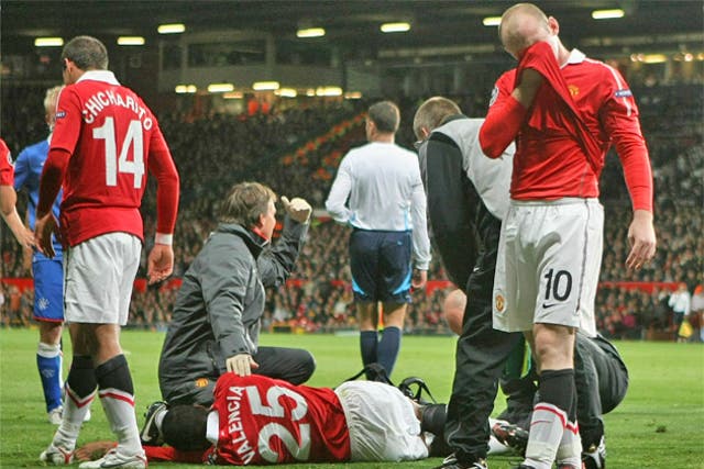 Wayne Rooney (right) cannot look as Antonio Valencia receives treatment following his horrific injury