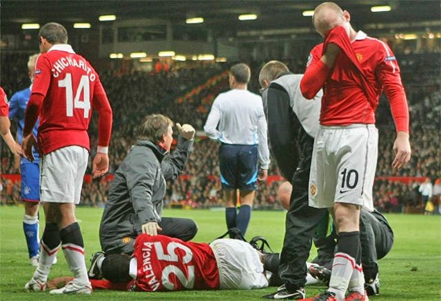 Wayne Rooney (right) cannot look as Antonio Valencia receives treatment following his horrific injury