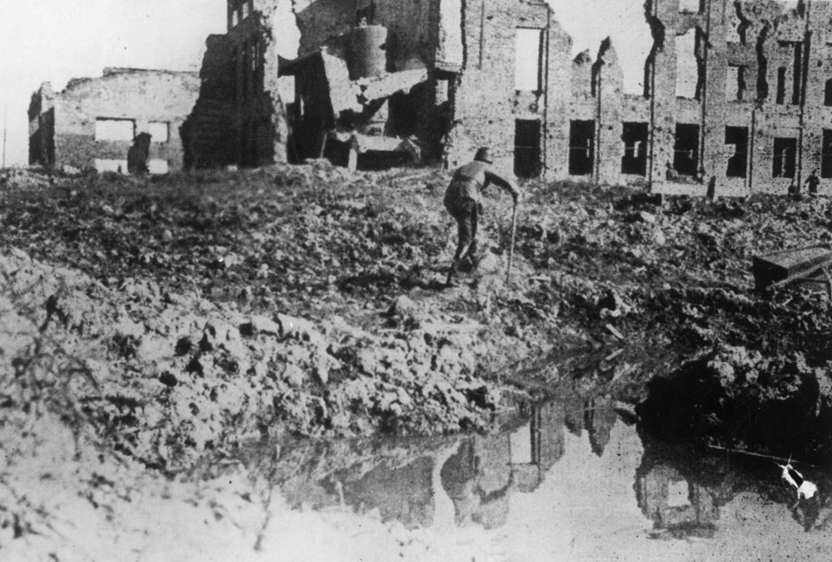 A lone German soldier hobbles round a waterlogged crater in which are reflected the devastated buildings of Stalingrad.