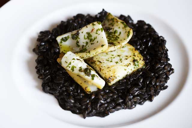 Spelt cooked in ink with squid and herbs is a British version of Spanish arroz negro