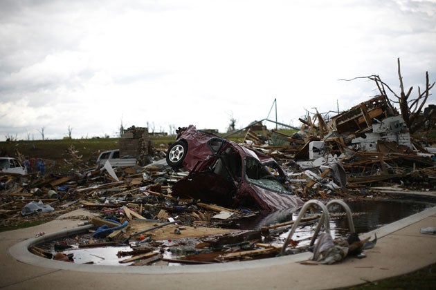 A car lies half submerged in a swimming pool in the backyard of a home, which is destroyed by a tornado in Joplin, Missouri