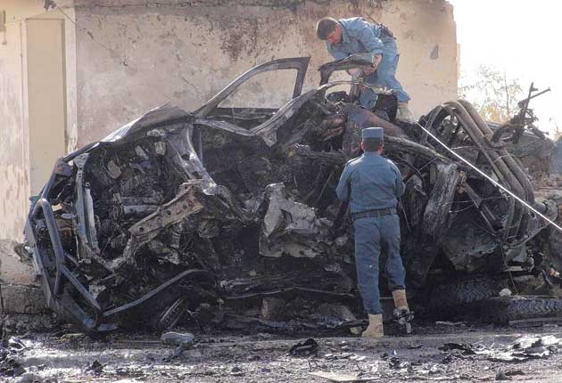 Police officers examine the scene of the suicide car bomb blast