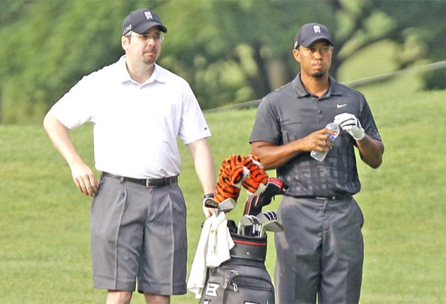 Tiger Woods sizes up a shot with new caddie Bryon Bell during practice yesterday for the Bridgestone Invitational in Akron, Ohio, which starts tomorrow