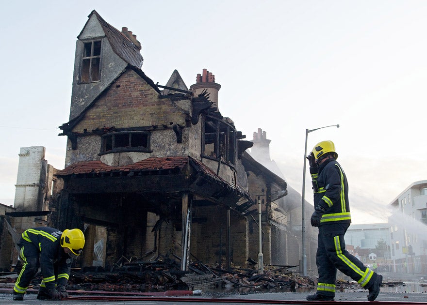 Firemen douse the charred remains of the Reeves furniture store in Croydon last August
