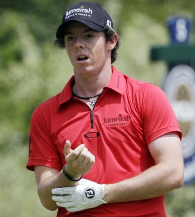 Rory McIlroy holds his wrist in pain after hitting a drive off the fifth tee