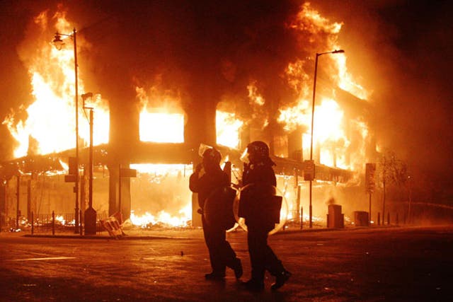 Riot police are powerless as flames engulf a building in Tottenham, north London, last weekend