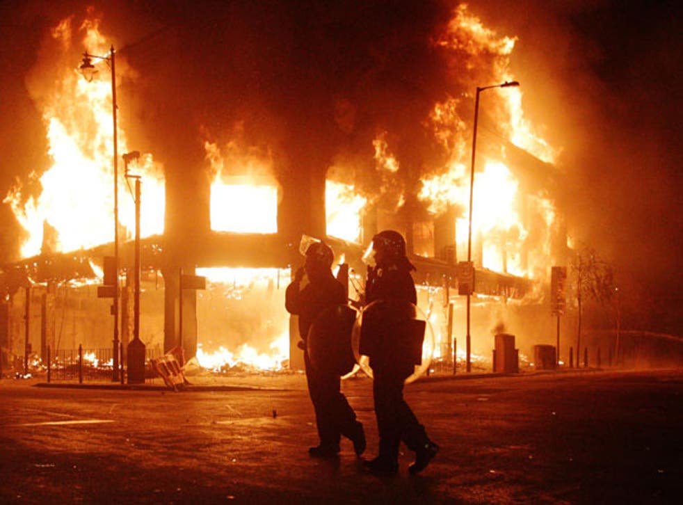 Riot police are powerless as flames engulf a building in Tottenham, north London, last weekend