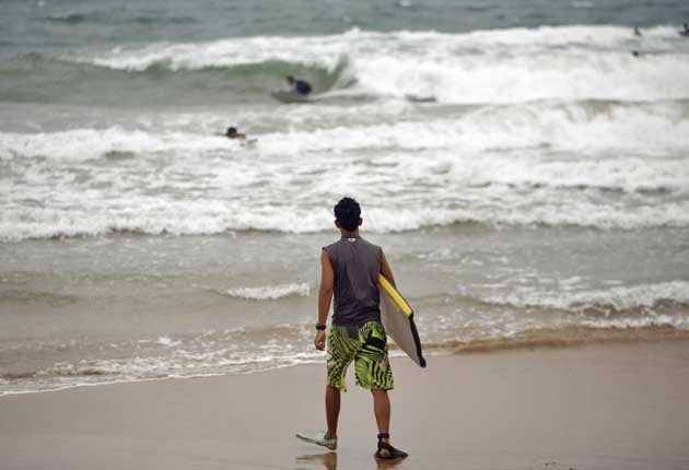 A surfer walks into the ocean as tropical storm Irene approaches to the island in Luquillo, Puerto Rico