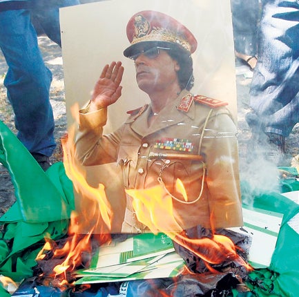 An image of Libyan dictator Colonel Gaddafi goes on the bonfire, wrapped in the old flag