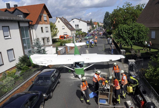 Firefighters stand near the Cessna sport plane in Stockstadt am Main, Germany