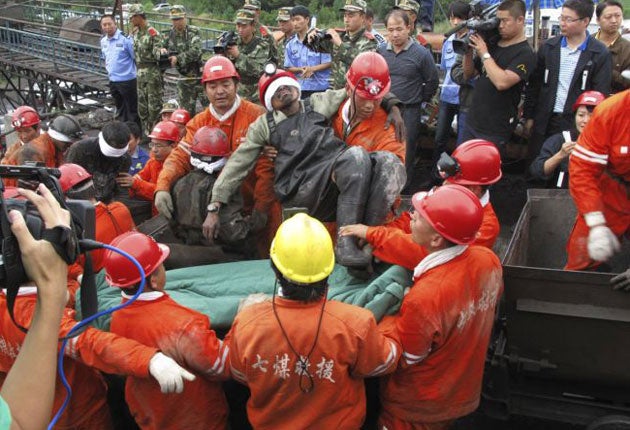 Rescuers carry a survivor out of the flooded pit at Hengtai coal mine