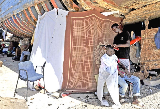 A refugee gets a haircut beneath an old ship in the port of Sidi Bilal. Aid groups say 1,000 such refugees are hiding at the makeshift camp, fearing they could be accused of being mercenaries for Colonel Gaddafi